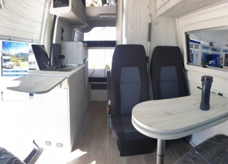 Furgoneta nueva, 
IVECO Camper,
Modelo  35S16A8V de 12m3,
Con cambio automático Hi Matic de 8 velocidades.  IVECO Daily Camper, una de las opciones más amplias del segmento con un espacio habitable de 12 metros cúbicos, con una longitud de 6 metros y una altura interior de 1,9 m. No obstante, estas dos últimas cifras pueden crecer hasta los 2,1 m de altura y 18 m3 de capacidad. Su carrocería presenta una amplia puerta corredera en el lateral derecho, escalón posterior y unas puertas traseras con apertura de 270º, sin olvidarnos de un habitáculo plano sin obstáculos. Su configuración polivalente permite que hasta 4 pasajeros viajen y pernocten en ella, con dos camas de matrimonio desmontables.  Toma como base la Daily destinada para uso profesional con mecánica diésel 2,3 litros Heavy Duty de 156 CV y 380 Nm de par motor, y cambio automático de 8 velocidades Hi Matic, destacando por ser una de las furgonetas con mayor maniobrabilidad del segmento.  Asimismo, cuenta con diversas ayudas sumamente interesantes para quienes no están acostumbrados a conducir este tipo de vehículos, como es por ejemplo el asistente de viento lateral.  Respecto a su interior, dice la marca que ha empleado materiales ligeros y duraderos basados principalmente en varios tipos de plásticos. Así pues, nos encontramos con un espacio capaz de albergar a cuatro huéspedes perfectamente equipado. La parte trasera se ha pensado de forma modular, pues cumple las funciones de dormitorio con una litera compuesta por dos camas de matrimonio de 198 x 130 cm con un baúl de almacenaje, comedor para esas cuatro personas, así como maletero con capacidad suficiente para guardar en él unas bicicletas o una pequeña motocicleta.  Dispone también de un baño completo con inodoro, lavabo y ducha, además de una cocina con dos fuegos, fregadero de un seno y nevera-congelador de 75 litros, estando todas las “estancias” perfectamente iluminadas gracias a las tres claraboyas y una iluminación interior 100 % LED. En cuanto al abastecimiento, corre a cargo de un depósito de 90 litros de aguas sucias y limpias y de una una placa solar de 160 W, siendo además capaz de suministrar corriente a 220 V con una potencia máxima de 1.500 W.  No obstante, para quienes prefieran tomar el aire fresco incluye un toldo de 3,7 metros y un foco LED bajo el cual poder colocar la mesa y sillas de camping. En el apartado multimedia cuenta con lo más esencial, como es una radio DAB, conexión USB y manos libres Bluetooth, aunque carece de la ya necesaria conectividad Android Auto y Apple CarPlay.